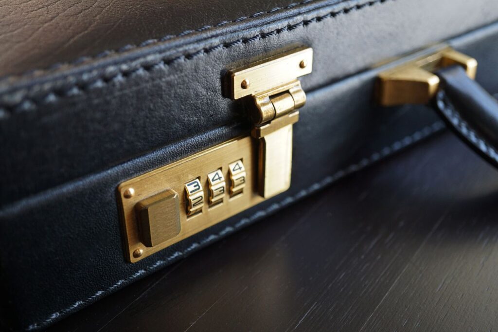 Close-up of a black leather briefcase with a brass combination lock for business security.